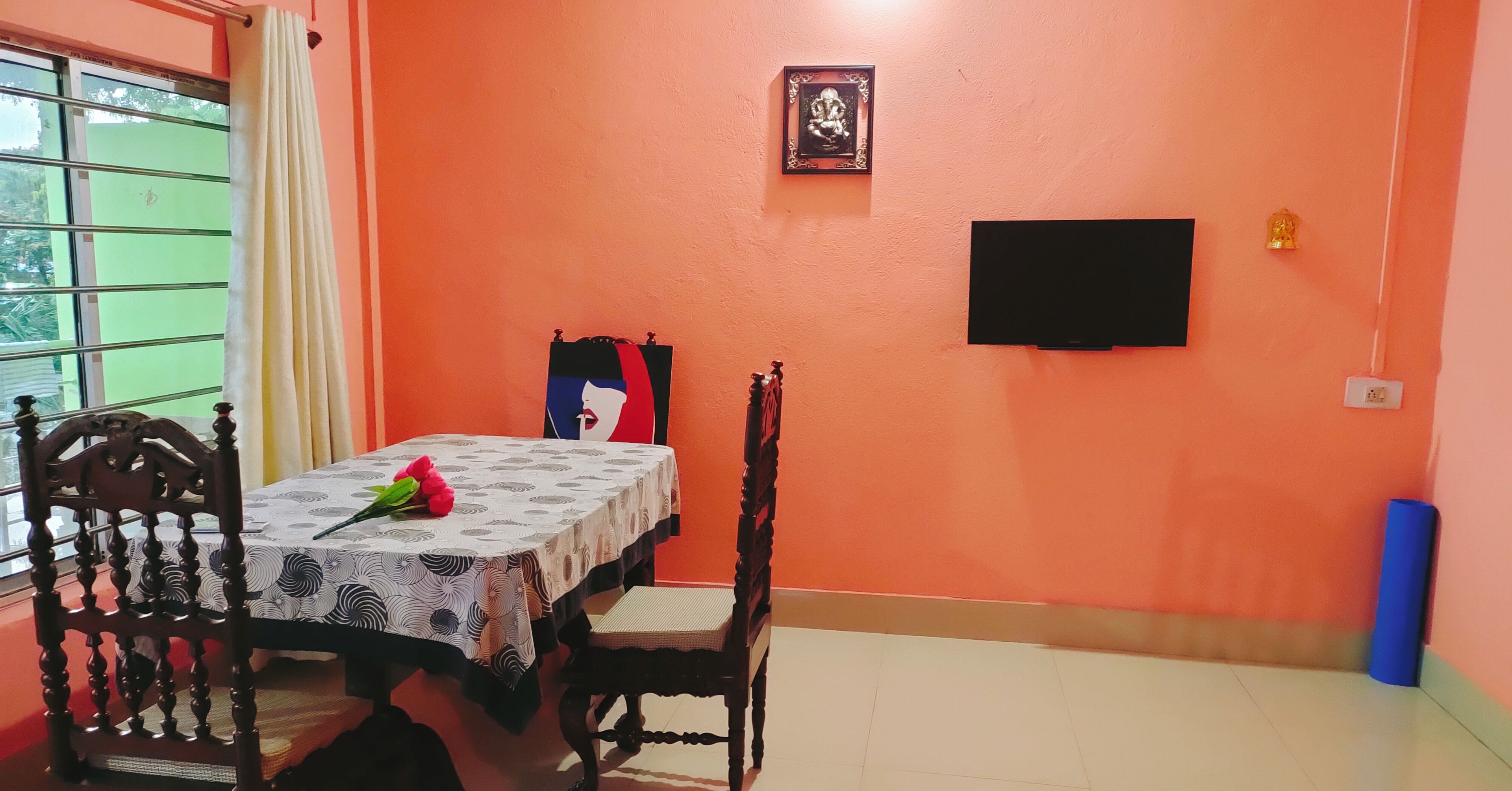 A dining area with a table, chairs, a TV, and a framed picture on the wall.