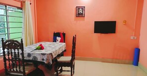 A dining area with a table, chairs, a TV, and a framed picture on the wall. - Couple friendly space. (Tezpur)