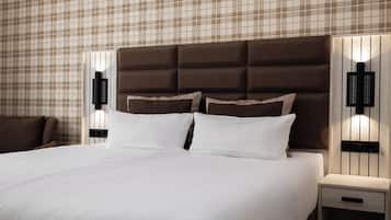 A hotel room with a large bed, a headboard, two bedside tables with lamps, and a plaid-patterned wall.