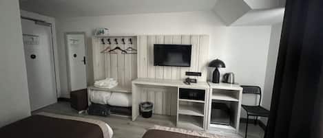 Habitación de hotel con dos camas, un escritorio, un televisor, perchero y un cubo de basura.