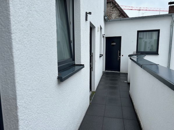 A narrow, white-walled corridor with a dark door marked "1408" and a window on the right.