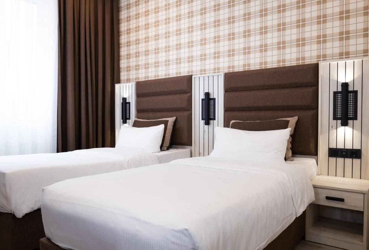 A hotel room with two beds, a checkered wall, and bedside lamps.