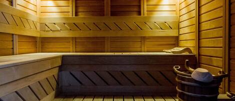 A wooden sauna with benches and two wall-mounted light fixtures.