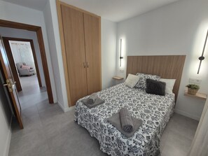 A bedroom with a bed, a wardrobe, a bedside table, and a nightstand.
