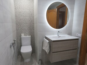 A modern bathroom with a toilet, sink, and shower.