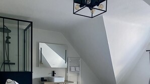 Um quarto moderno com uma cama grande, uma mesinha de cabeceira, um espelho e um lustre.