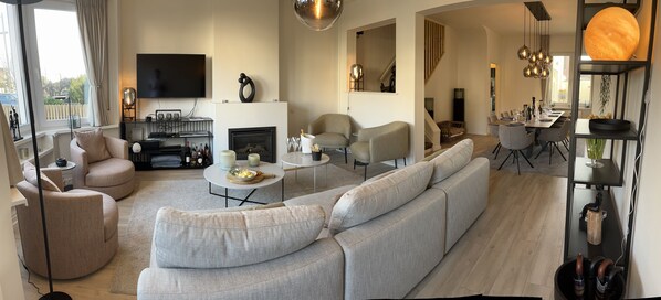 A modern living room with a large sofa, a dining area, and a fireplace. - Instant Knokke (Knokke-Heist)