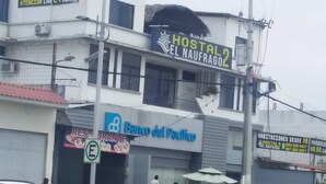 Un edificio con un cartel que dice 'Hostal El Naufra 2' y 'Banco del Pacífico', y un letrero de estacionamiento con la letra 'L'.