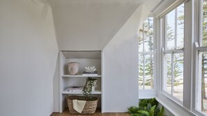 A corner room with a white shelf, a woven basket, and a window with a view of trees. - The Ryokan - Zen (Manly)