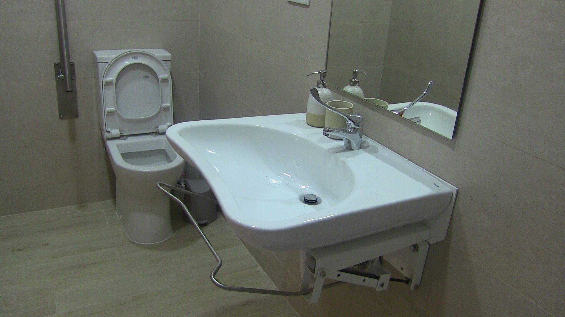 A bathroom with a toilet, sink, and mirror.