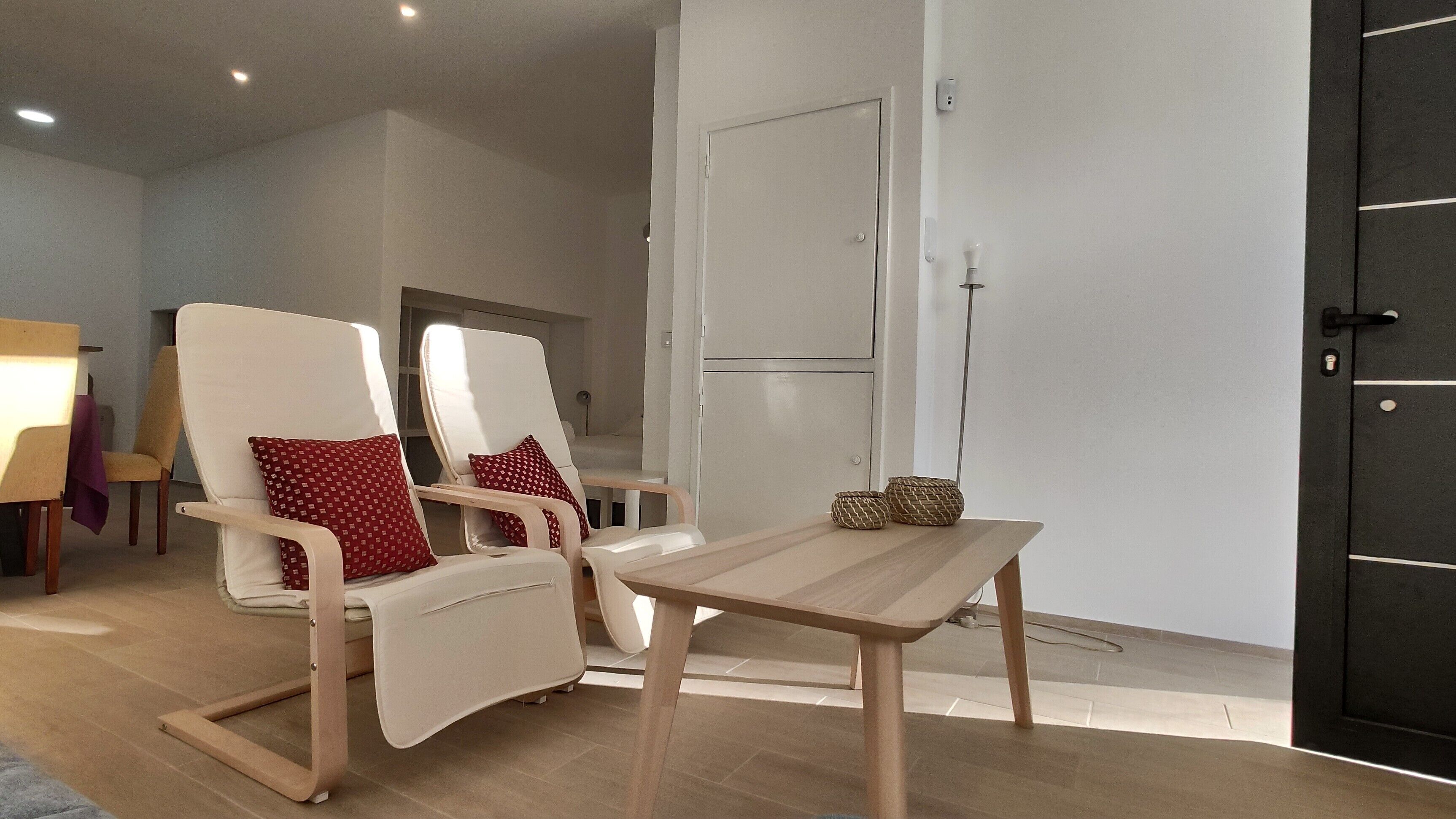 A modern living room with two reclining chairs, a wooden coffee table, and a black door.