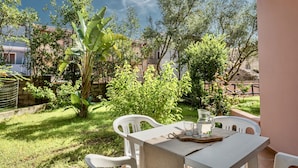 An outdoor patio with a table and chairs, surrounded by greenery and trees. - I Mirti Bianchi Residence con piscina (Santa Teresa di Gallura)