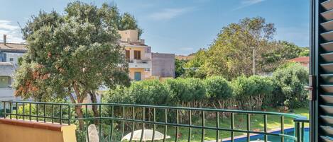 A balcony with a view of a pool, greenery, and buildings in the background.