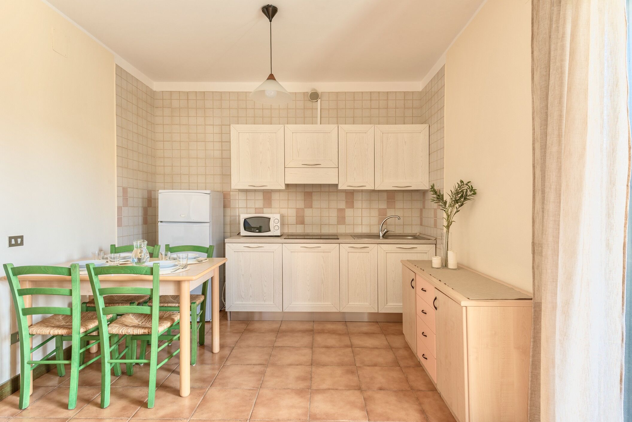Une cuisine compacte comprenant une table et des chaises, un four à micro-ondes et un évier.