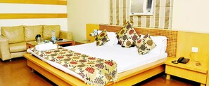 Una habitación de hotel con cama, mesita de noche, sofá y unidad de aire acondicionado.
