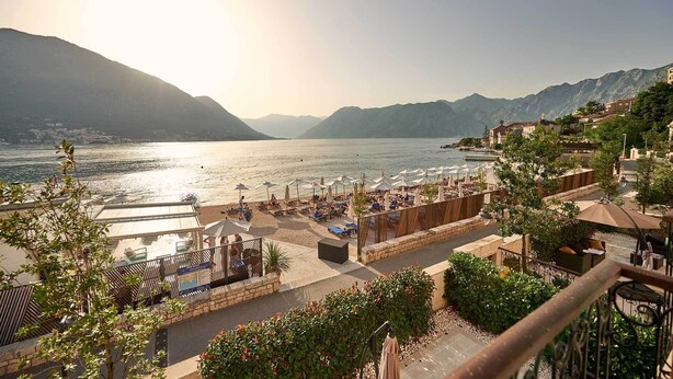 Un hôtel situé sur la côte, doté d’une terrasse, d’une piscine et offrant une vue sur les montagnes.