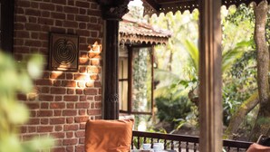 A covered outdoor seating area with brick walls and wooden furniture. - Amã Stays & Trails Asanji Wadi (Alibag)