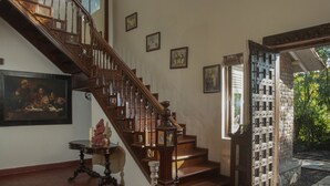 A grand staircase with intricate woodwork, leading to a second floor. - Amã Stays & Trails Asanji Wadi (Alibag)