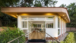 Un bâtiment moderne doté d’une façade en verre, d’une terrasse en bois et d’un escalier menant à une entrée abritée.