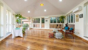 Une pièce spacieuse avec un plancher en bois, de grandes fenêtres et un ventilateur de plafond.