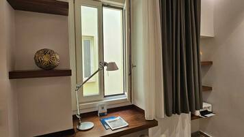 Una habitación moderna con escritorio, lámpara y ventana con cortinas.