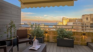Terraza en la azotea con mobiliario de mimbre, plantas en macetas y vista al mar.