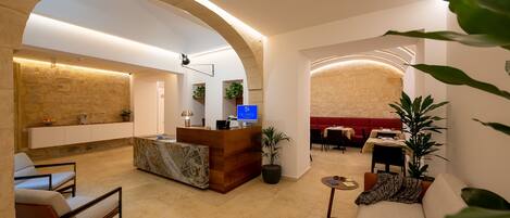 A hotel lobby with a reception desk, seating area, and a red sofa.