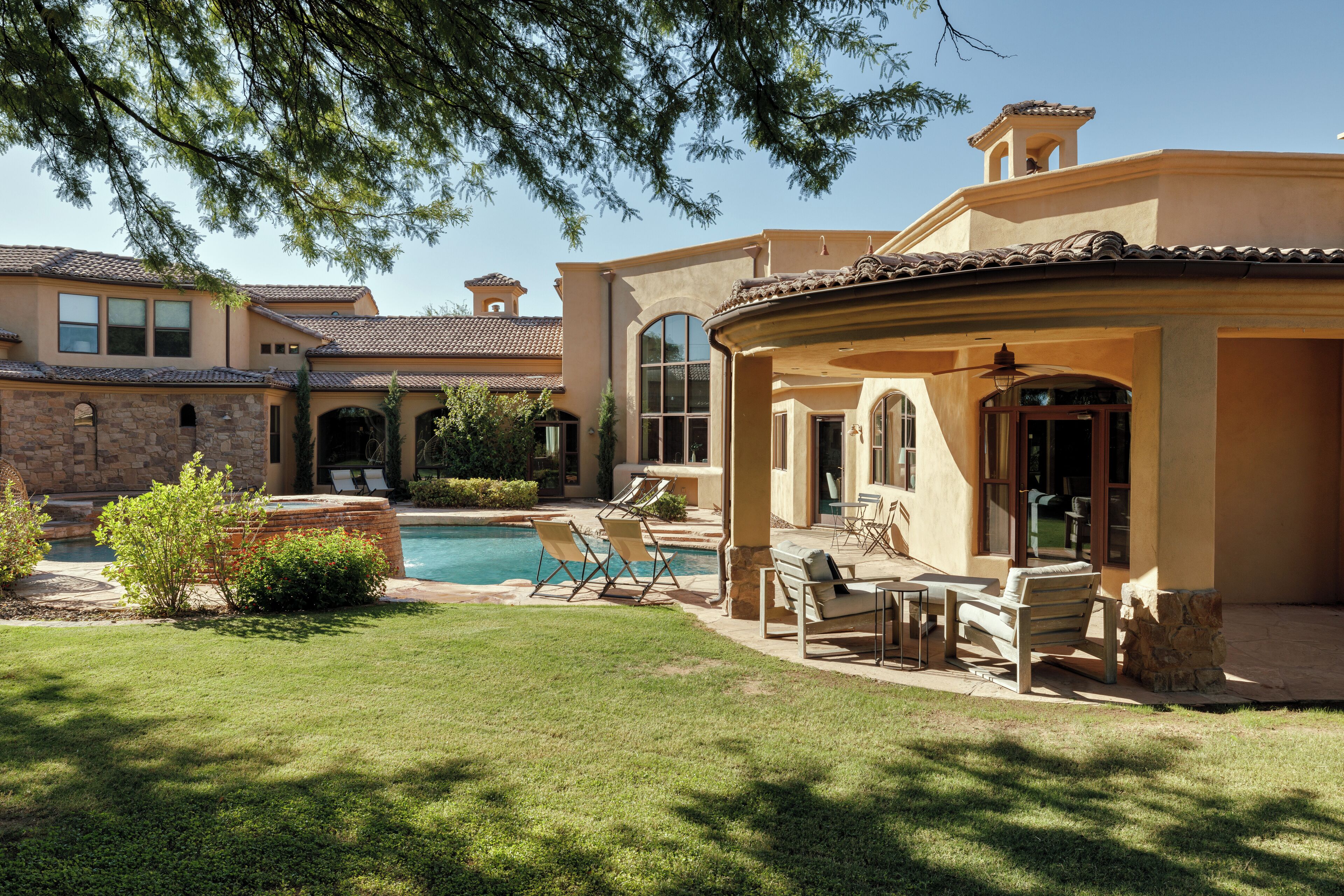 A house with a swimming pool, outdoor seating, and a stone patio.