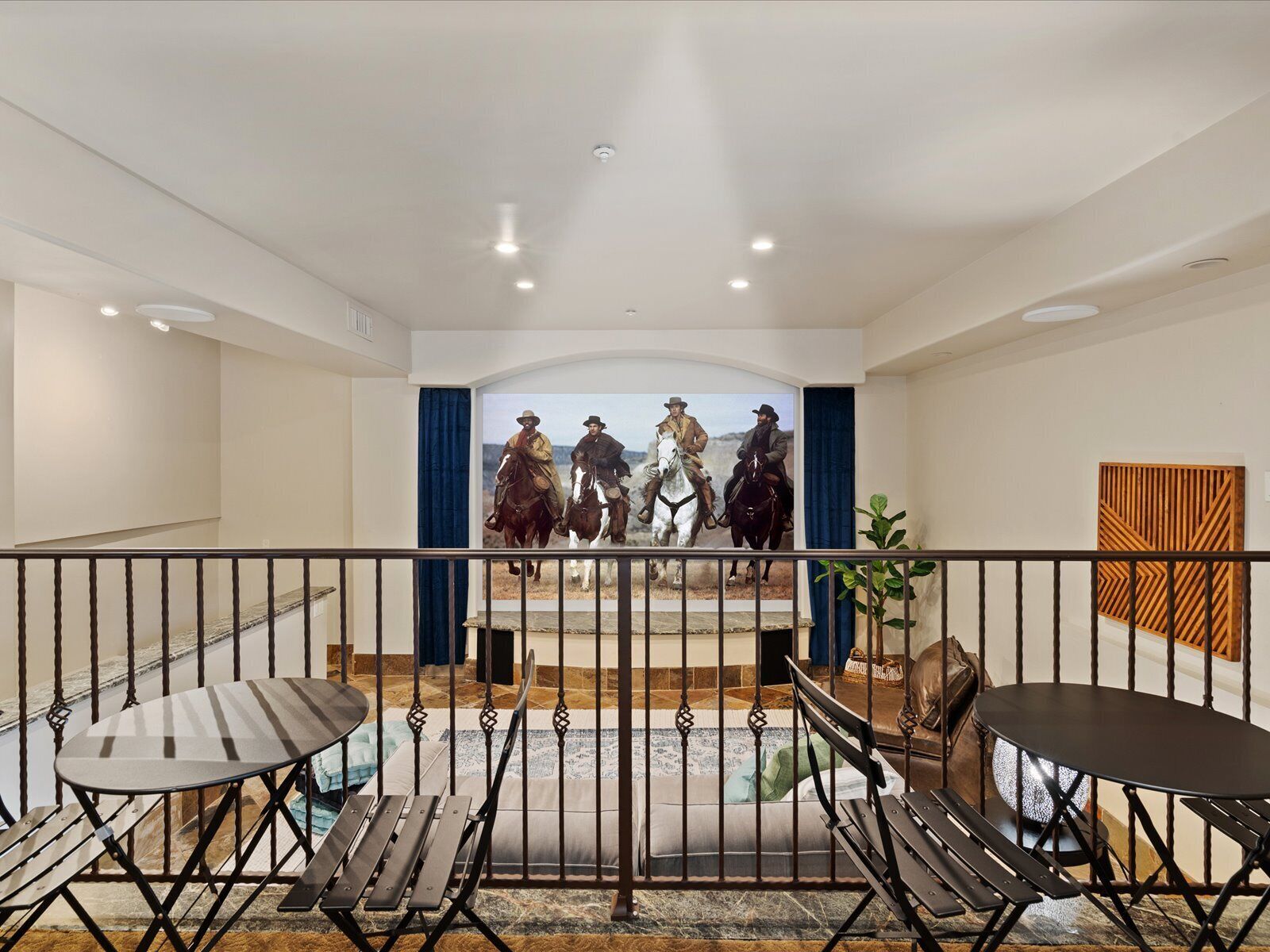 Un vaste balcon offrant une vue sur le paysage urbain, aménagé avec une table et des chaises, et agrémenté d’un panneau décoratif en bois sur le mur.