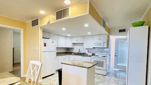 A compact kitchen with white cabinets, a central island, and a dining area with a table and chairs.