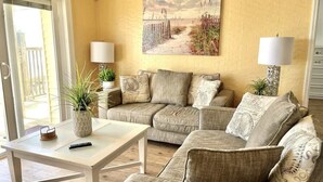 A living room with a sofa set, a coffee table, two lamps, and a painting on the wall.