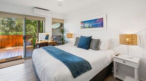 Ein Schlafzimmer mit Bett, Nachttisch, Lampe und Blick ins Freie.