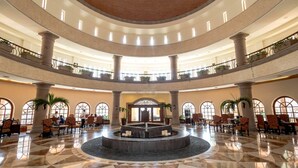 A spacious lobby with a central fountain, multiple seating areas, and a high ceiling with skylights.