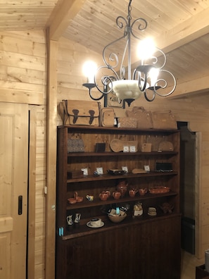 A wooden interior with a chandelier, shelves of pottery, and a wooden door.
