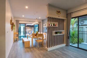 Una sala de estar moderna con comedor, ventanas amplias y vistas al exterior.