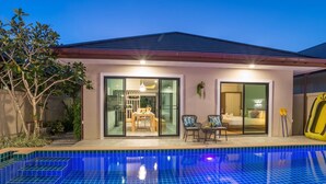 A modern house with a swimming pool, large glass doors leading to a dining area, and a yellow inflatable pool. - Love ao nang pool villa  (อ่าวนาง)