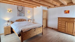 Un dormitorio con cama de madera, mesitas de noche, cómoda y luces en la pared.