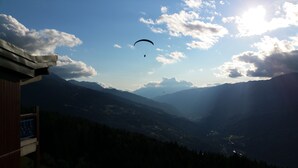 Een bergachtig landschap met een persoon die paragliding doet.