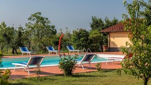 A swimming pool with lounge chairs, surrounded by greenery and a small building with a red-tiled roof. - Torriano 4 (San Casciano Val di Pesa)