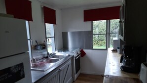 A kitchen with white cabinets, a stainless steel range hood, a sink, and a coffee maker. - The Meuse is at the end of the garden (Fépin)