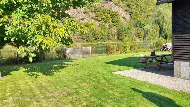 A well-maintained lawn with a picnic table and a wooden fence. - The Meuse is at the end of the garden (Fépin)