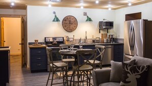 A modern kitchen with a central island, wooden ceiling, and built-in appliances.