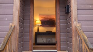 A wooden staircase leading to a room with a lamp, a picture on the wall, and a small console table.