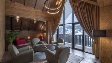 A cozy lounge area with a large window, wooden ceiling beams, and comfortable seating.