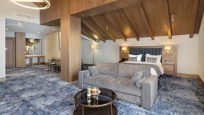 Ein Hotelzimmer mit einem großen Bett, einer Schlafcouch, einem Couchtisch mit Tablett und einer Holzzieldecke.