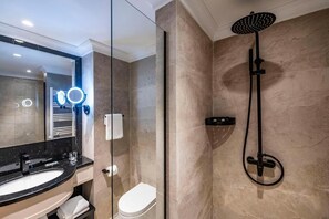 A modern bathroom with a glass-enclosed shower, a vanity with a black countertop, and a large mirror with lights.