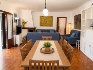 A dining area with a table set for four, flanked by two sofas and a television.