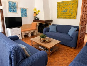 A living room with a sofa set, a television, a fireplace, and artwork on the walls.