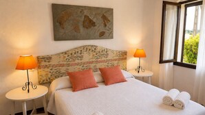 Une chambre d’hôtel avec un lit, deux lampes de chevet, une fenêtre avec des rideaux et un tableau au mur.