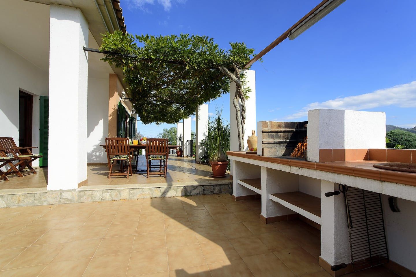 An outdoor patio with a table and chairs, a pizza oven, and potted plants.